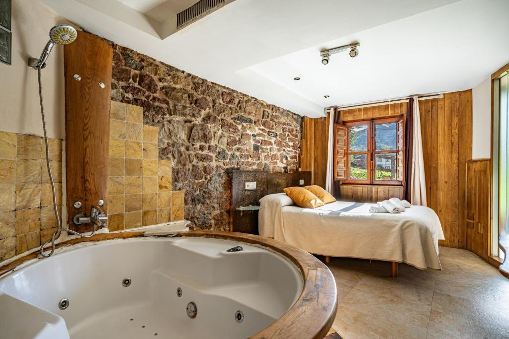 a bathroom with a bath tub and a bedroom at Aguas del Sella - jacuzzi in Precendi
