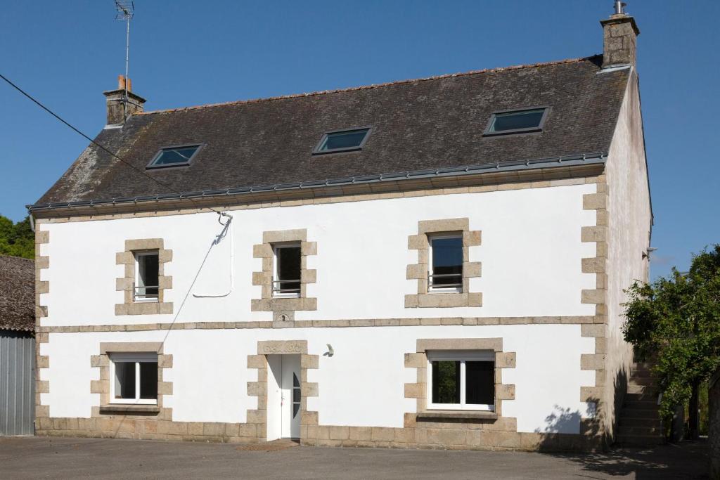 a white building with a gray roof at Maison de vacances Chez André in Meslan