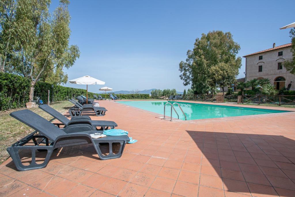 a swimming pool with lounge chairs next to a building at Appartamento Giglio in Riotorto