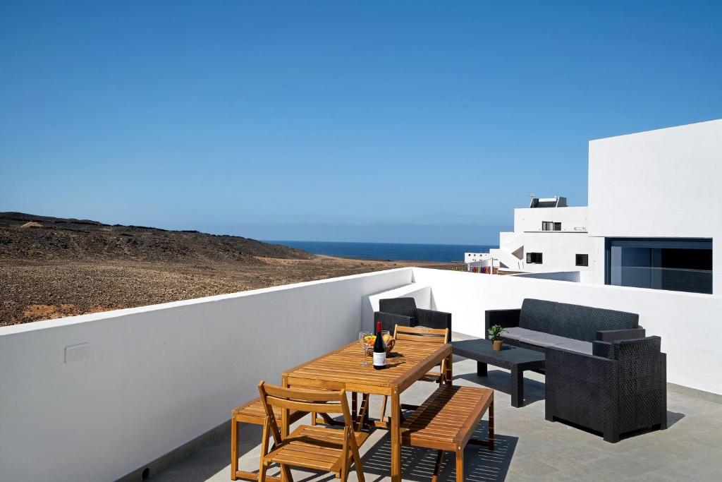 a patio with wooden tables and chairs on a white wall at Kay 4 in La Santa