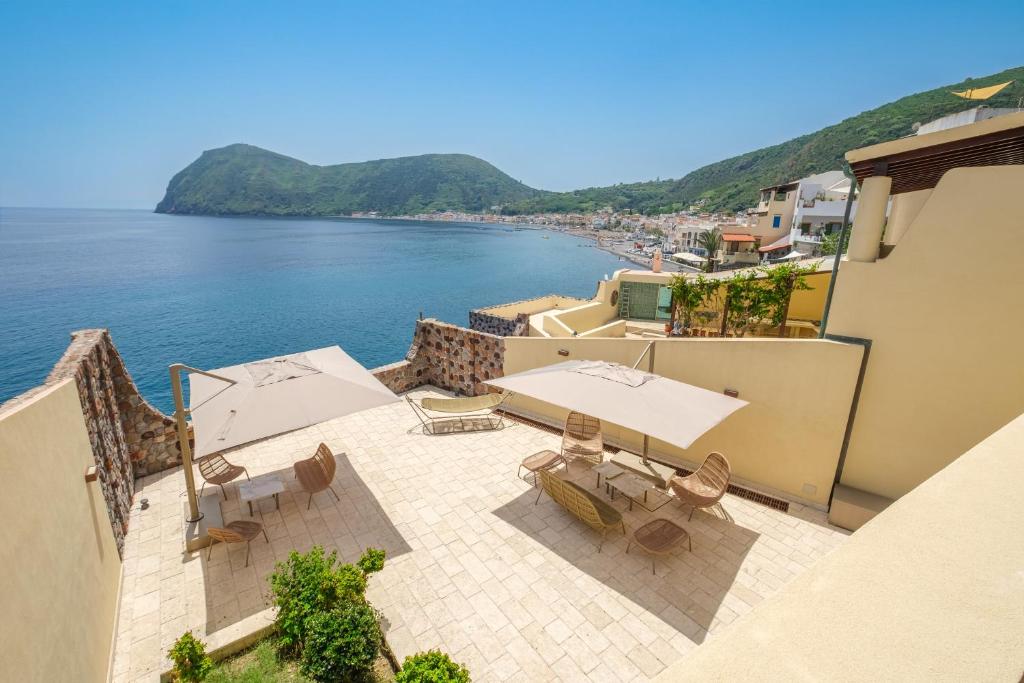 an outdoor patio with tables and chairs next to the water at Villa Chiara in Lipari