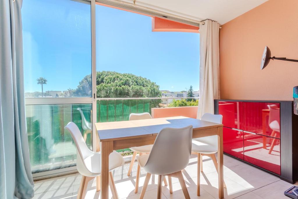 a dining room with a table and chairs and a large window at Azur et Lavande proche plage in Fréjus