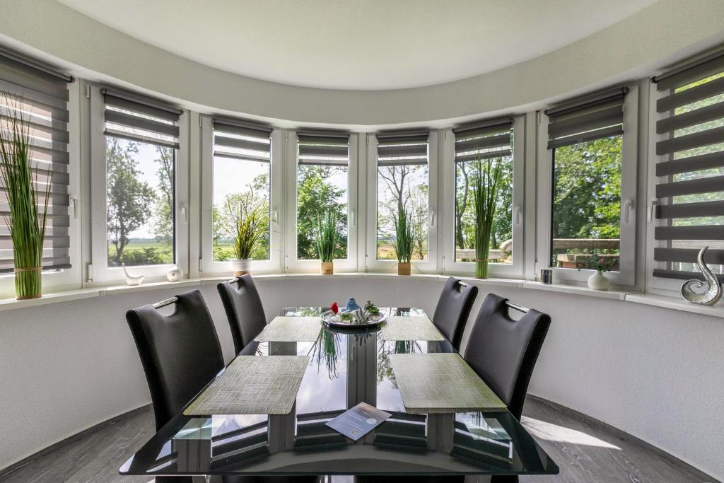 a dining room with a table and chairs and windows at Föhr in Galmsbüll