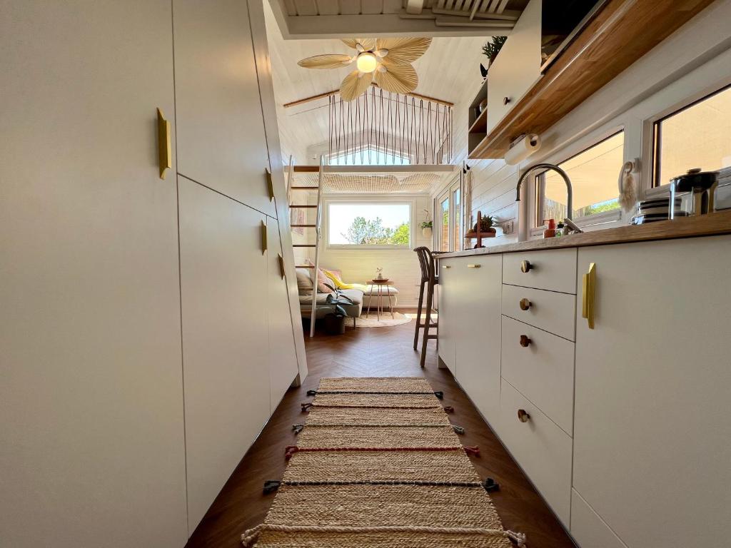 a kitchen with white cabinets and a rug on the floor at Tiny House Gänseblümchen in Kirchanschöring