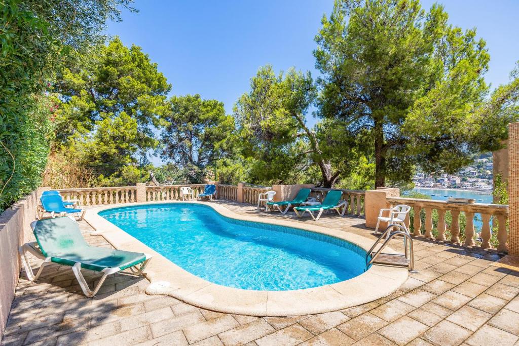a swimming pool with two chairs and a deck with at Traumblickwohnung Montemar 19 in Sóller