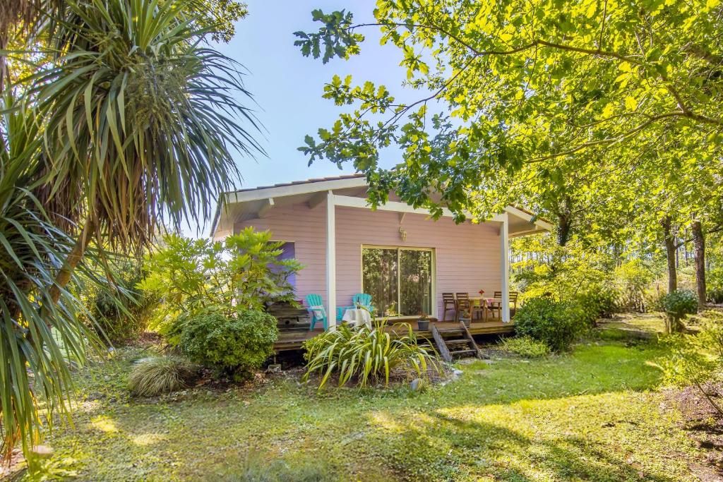 a small pink house with a patio in the yard at Joli Petit Chalet La Cote d'Argent in Le Porge