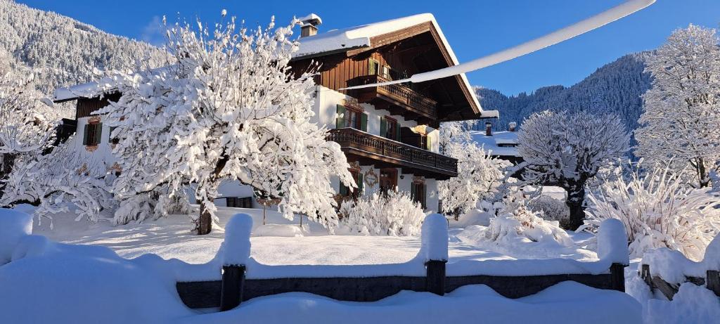 a house covered in snow with trees and a fence at Haus am Kurgarten - Seeberg in Bayrischzell