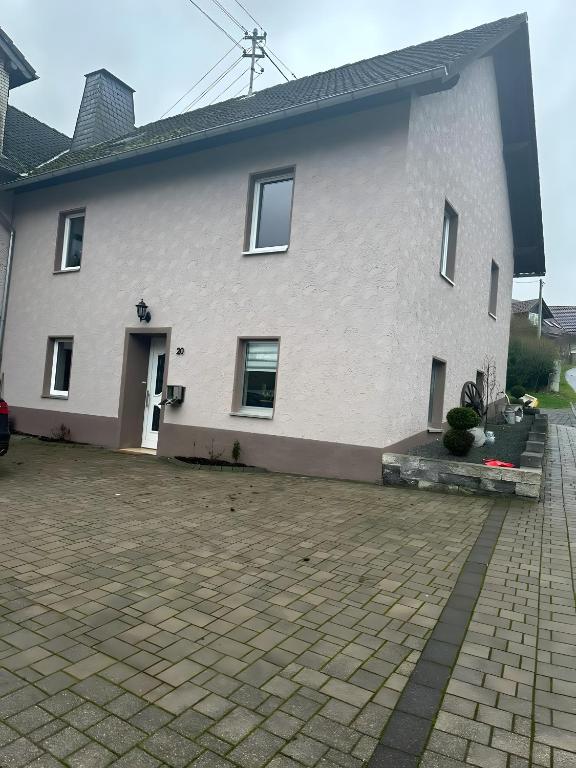 a large white house with a brick driveway at Ferienhaus Nosbers in Kleinlangenfeld