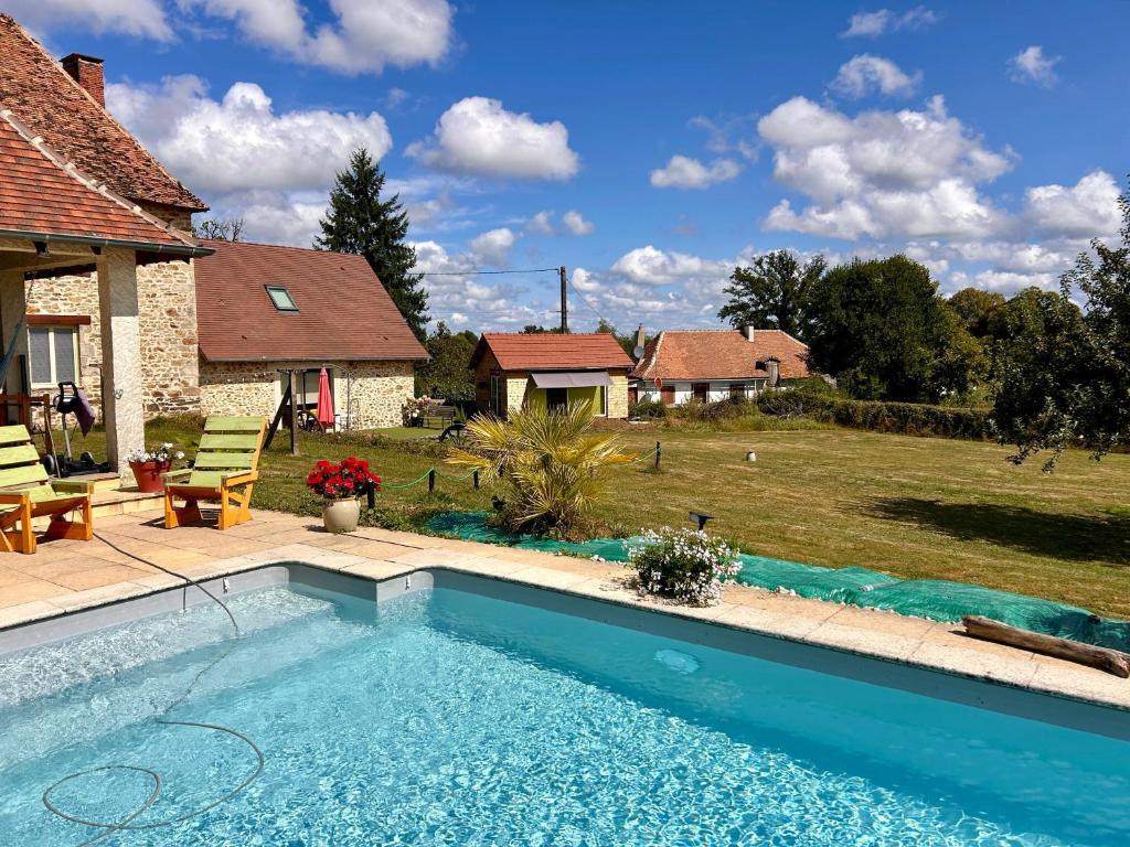 a swimming pool in front of a house with a yard at Gite Charmant Forme et Bien-etre in Masseret