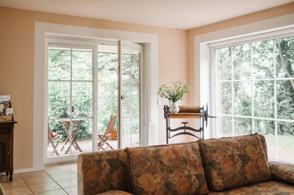 a living room with a couch and large windows at Landhaus Elbenberg in Naumburg