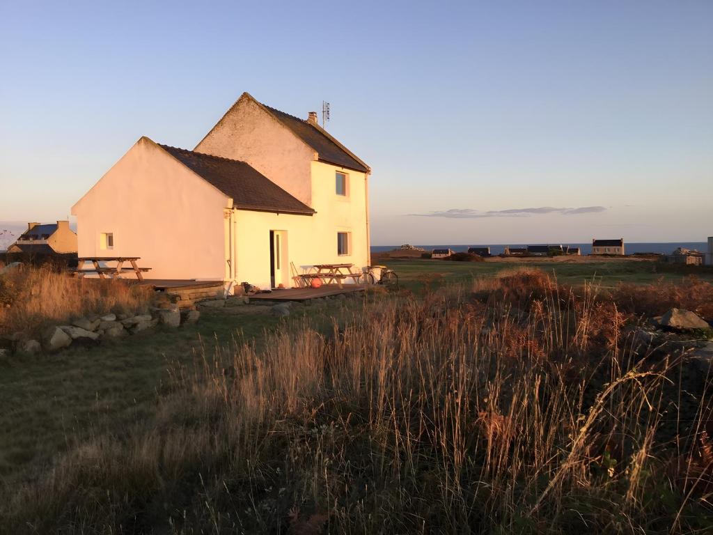 a house in a field with the ocean in the background at L'ancien Gonio de l'Île in Lampaul