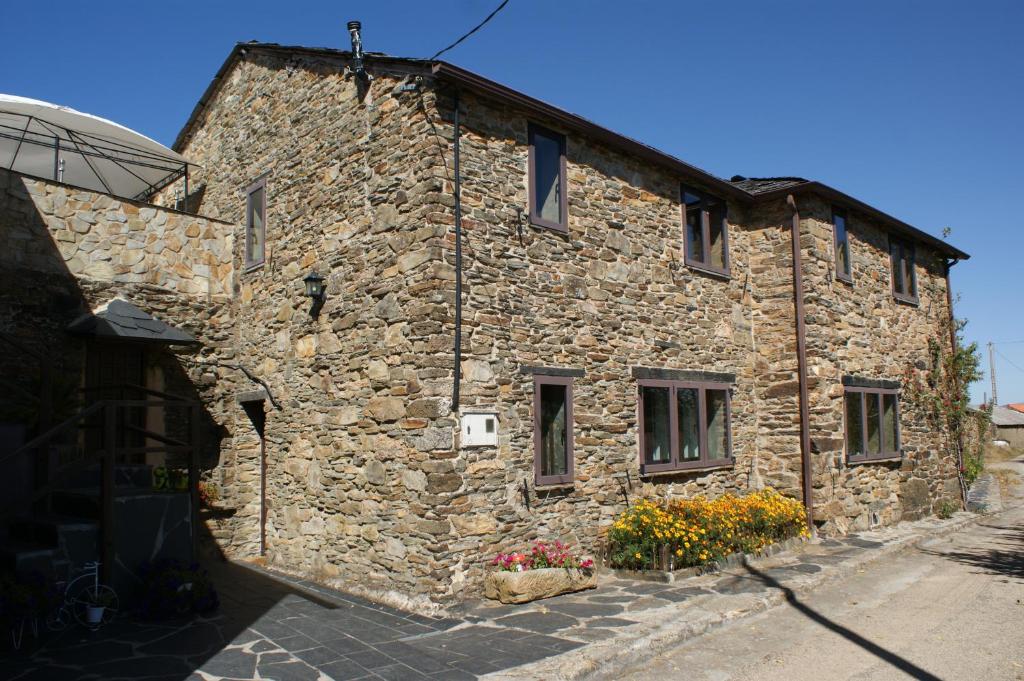 a stone building with flowers in front of it at O Bolaño Apt 2 in Villarino de Conso