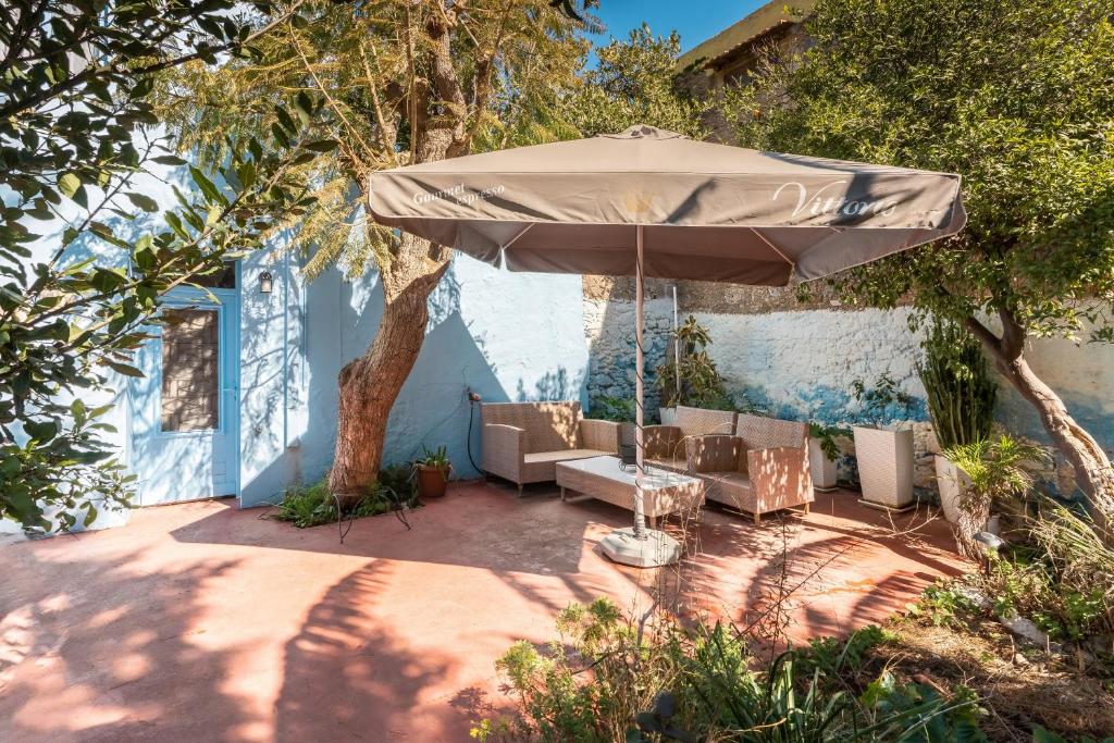a patio with an umbrella and chairs under a tree at Katia's Home in Rhodes Town