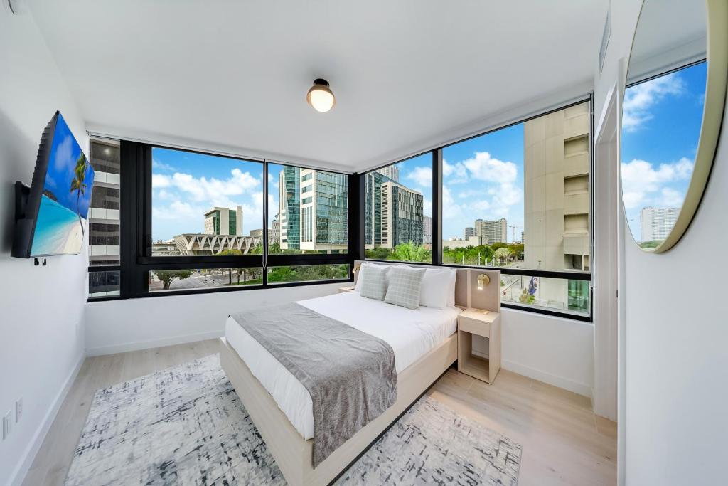 a bedroom with a bed and large windows at District 225 Condo by Ionica in Miami