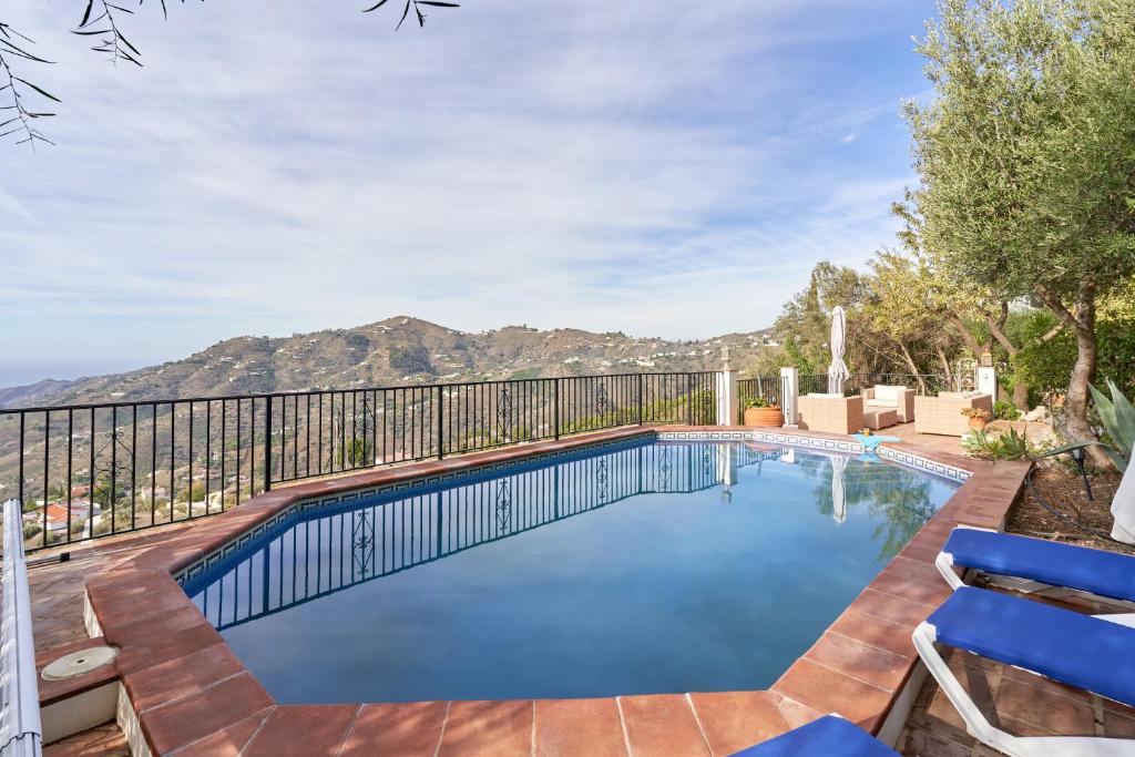 a swimming pool with a fence and blue chairs at Casa Oliana in Cómpeta