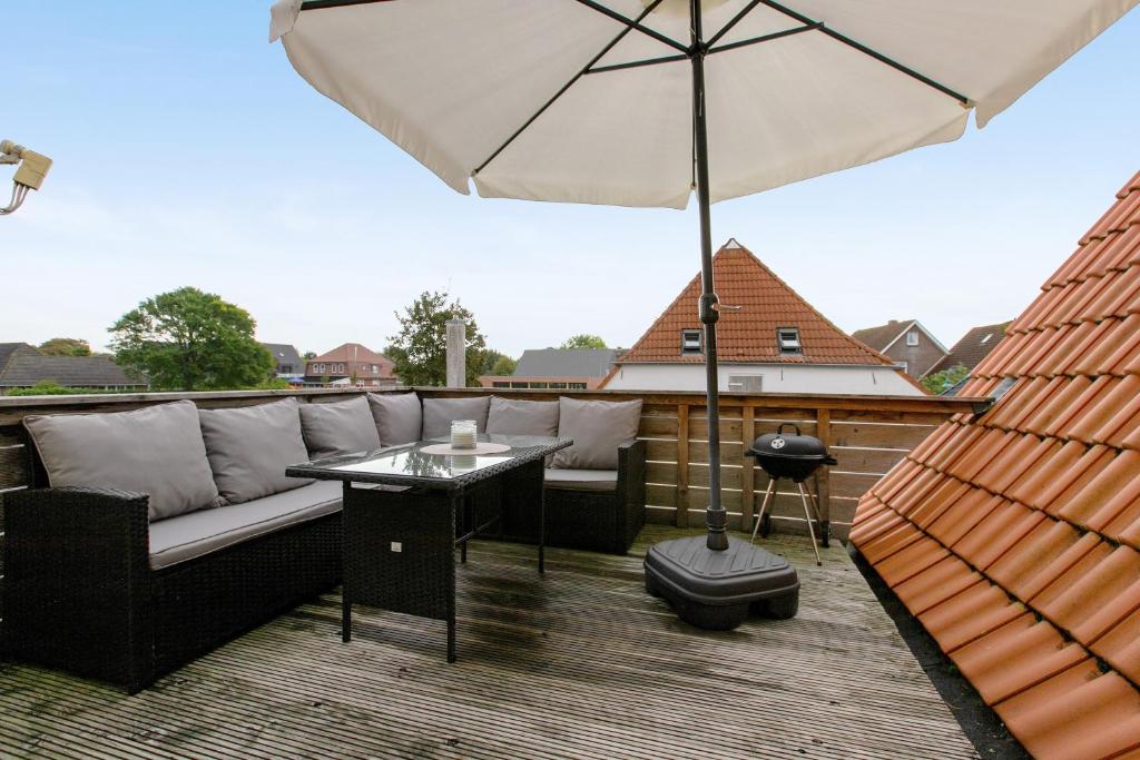 a patio with a couch and an umbrella on a roof at Ferienwohnung Janina in Norddeich