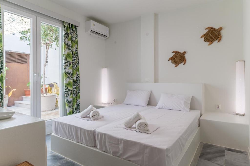a white bedroom with a bed with two towels on it at A Tinian Room 3 in Tinos