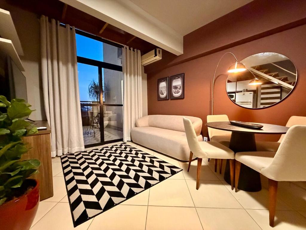 a living room with a table and chairs and a mirror at Central Duplex Loft Near USP in São Carlos