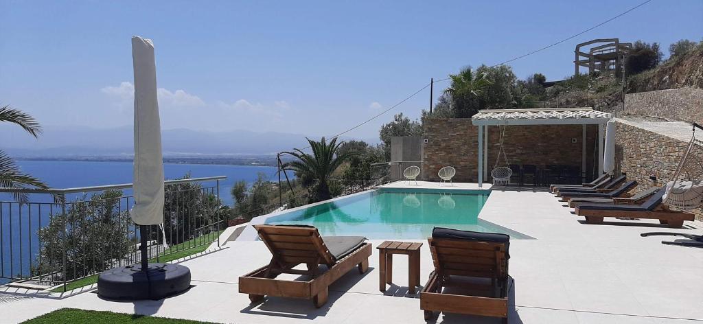 a swimming pool with two chairs and a table at ALBA OCEAN VIEW LUXURY RESIDENCE in Nea Anchialos
