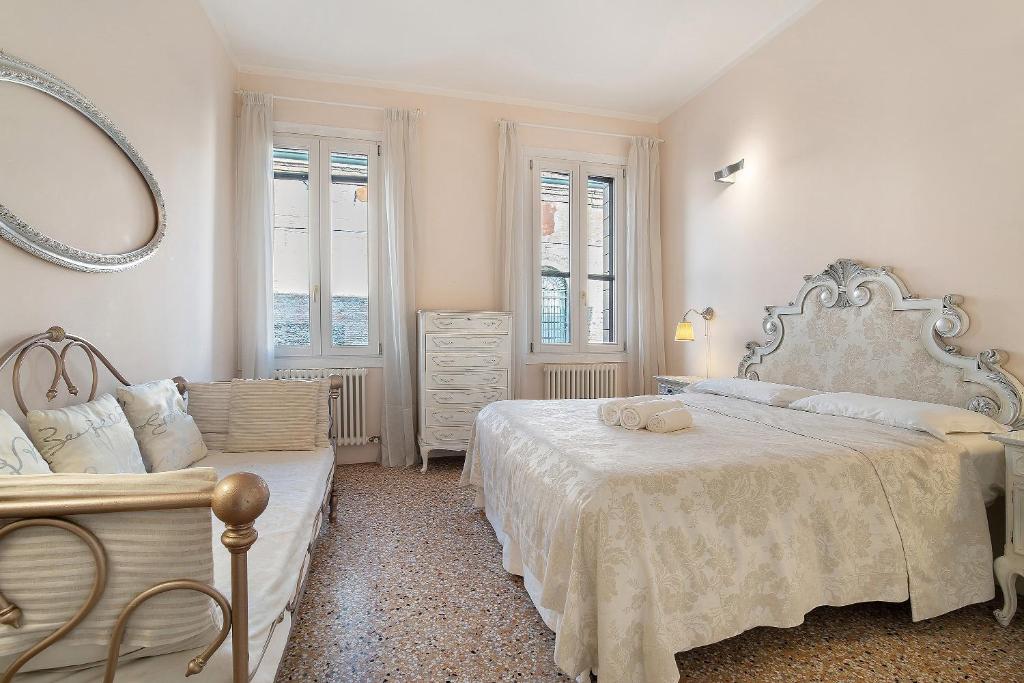 a white bedroom with two beds and a mirror at Biennale Apartment near San Marco in Venice