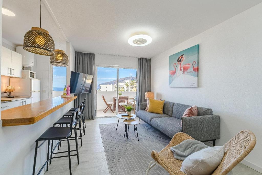 a living room and kitchen with a couch and a bar at Playa La Arena 2 Bed Apartment in Puerto de Santiago
