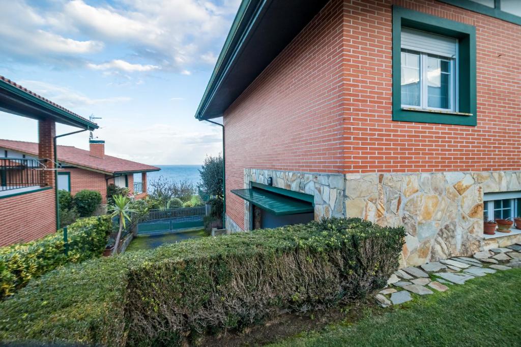 a red brick house with a window on the side of it at Villa La Perla De Sonabia in Oriñón