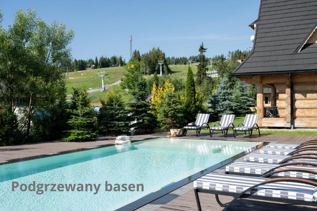 a swimming pool with lounge chairs and a house at Domki w Białce WOODHOUSE- Twój górski azyl przy stoku in Białka Tatrzańska