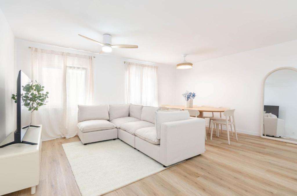 a white living room with a white couch and a table at Apartamento Bilua in Luanco