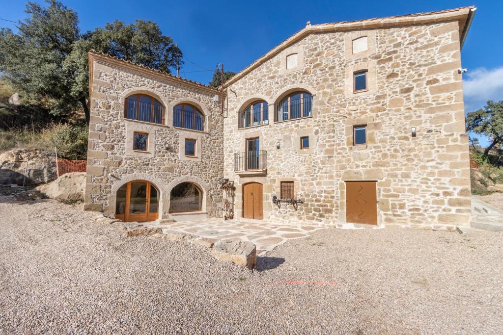 a large stone building with brown doors and windows at El Molí de Can Feliu in Navés