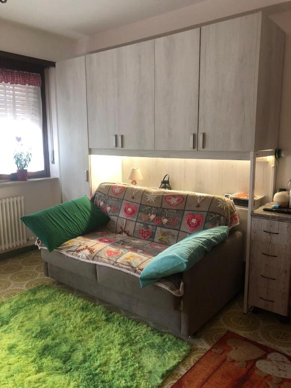 a bedroom with a couch with green pillows on it at L'oasi dei larici - Montoso in Bagnolo Piemonte