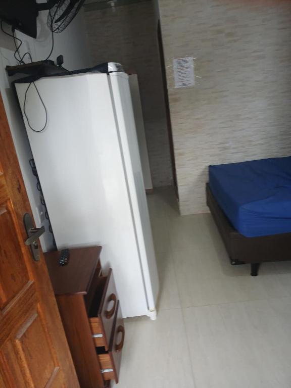 a small room with a bed and a refrigerator at Pousada Coutinho in Paraty