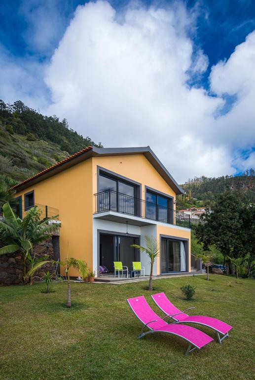 two pink lawn chairs in front of a house at Casa do Louro in Arco da Calheta