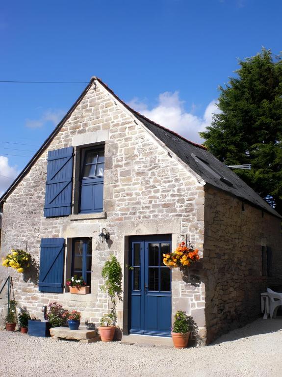 a stone house with blue doors and flowers in pots at Le Courtil De Bourrien in Languédias