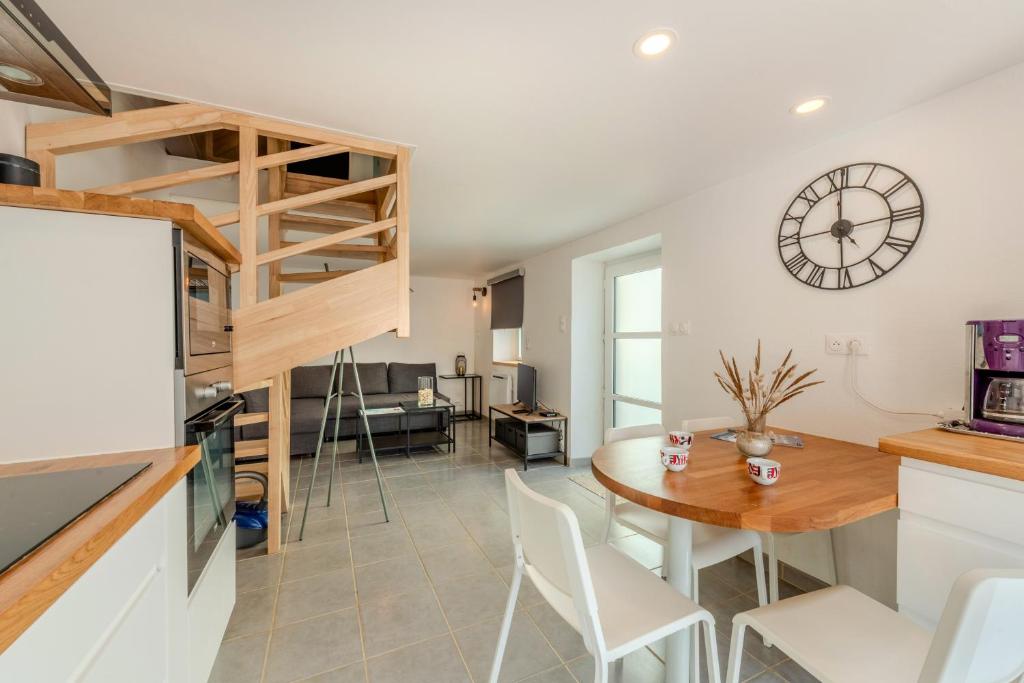 a kitchen and dining room with a table and a clock on the wall at Au Coeur De Plouguerneau in Plouguerneau