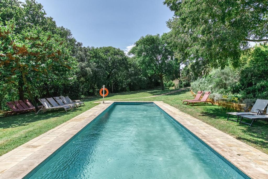a swimming pool in a yard with chairs and trees at Mas la Ginesta in Borrassá