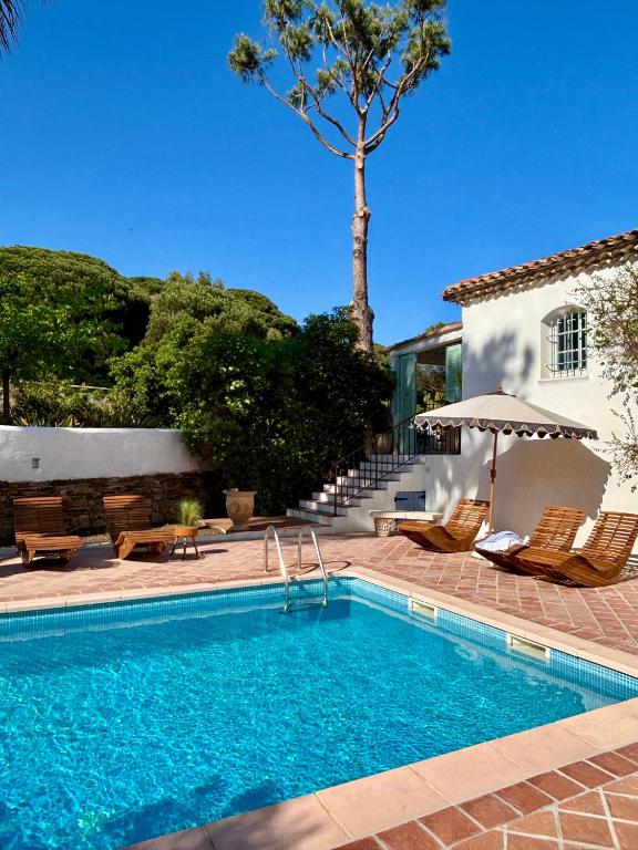 a swimming pool with chairs and an umbrella next to a house at Luxury family villa with large pool, garden & outdoor dining near beach, Domaine l'Oiseau Bleu in Sainte-Maxime in Sainte-Maxime