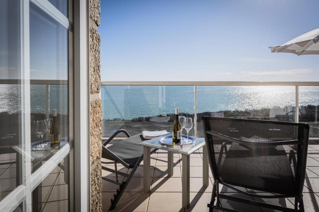 a balcony with a table and chairs with a view of the water at Hôtel de la Pointe du Grouin in Cancale