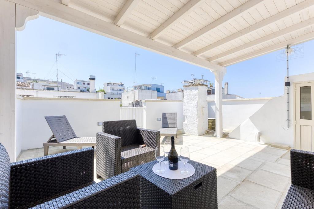 a patio with chairs and a table with a bottle of wine at Casa Don Michele in Specchia