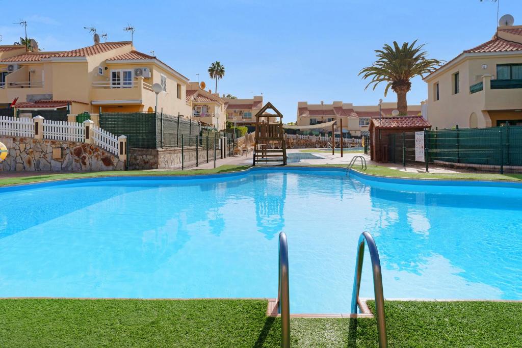 a large blue swimming pool in front of some houses at Bungalow Sonemar Paradise in Maspalomas