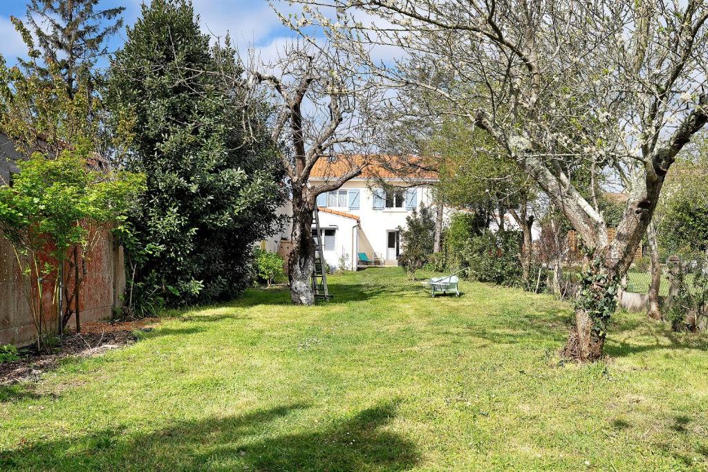 a yard with a bench in front of a house at Les Passiflores - Chambre d'Hôtes in Pornic
