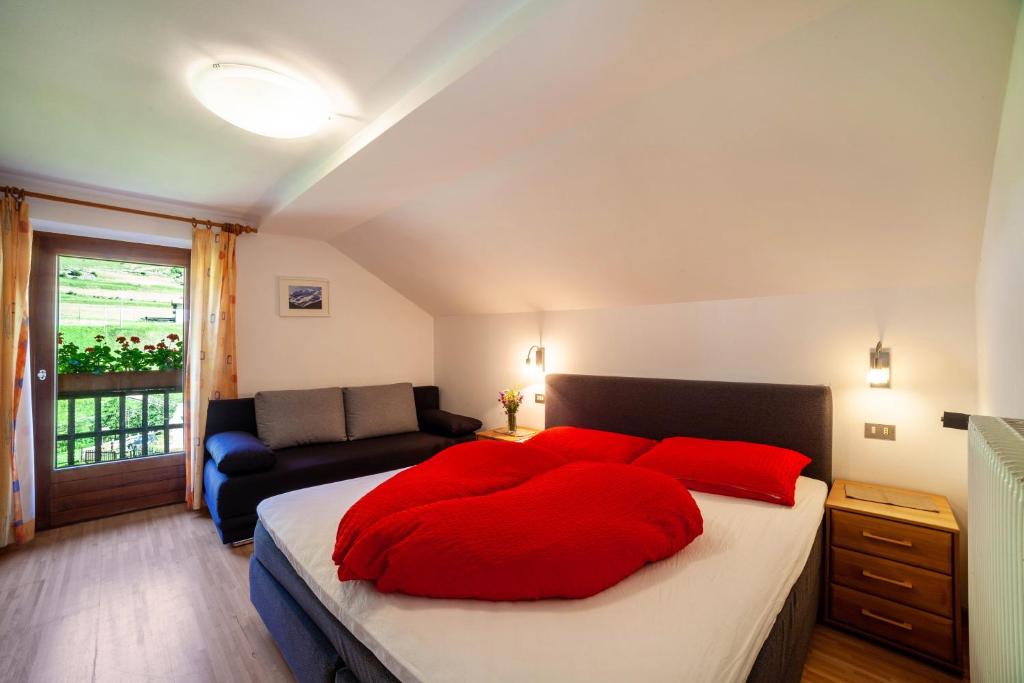 a bedroom with a large bed with red pillows at Rieglhof Apartment Kükennest in Curon Venosta
