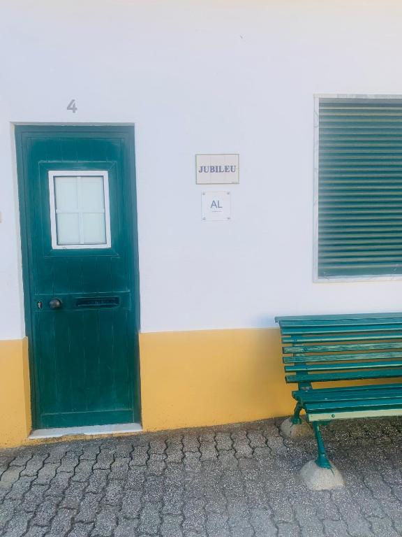 a green door and a bench in front of a building at Casa Jubileu in Golegã