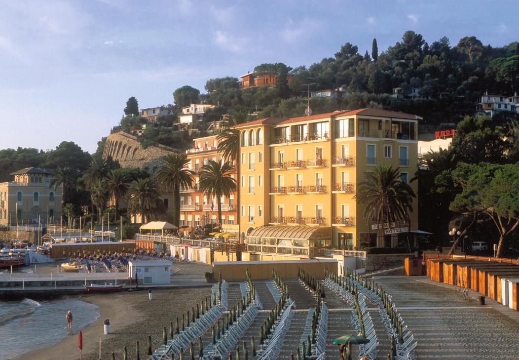 un gruppo di edifici vicino a una spiaggia con sedie di Jasmin Charme Hotel a Diano Marina