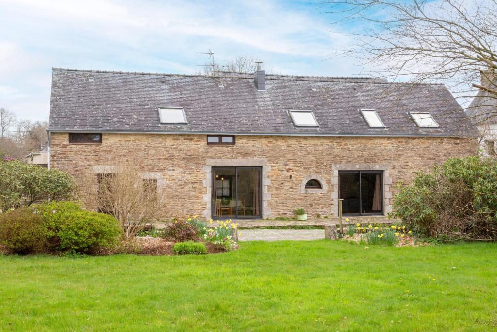 a large brick house with a roof at La longère familiale et authentique in Melgven