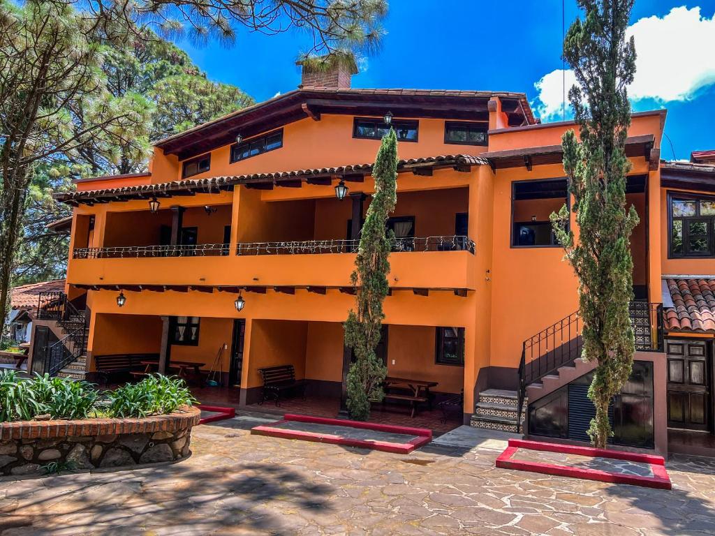 an orange building with trees in front of it at Villas Lupita in Mazamitla