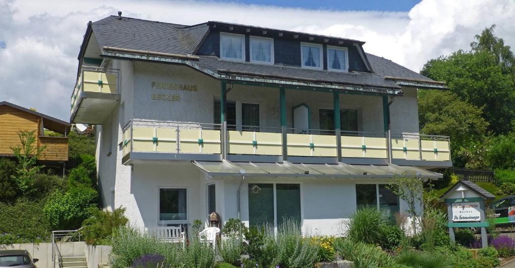 a white house with a balcony on top of it at Ferienwohnung Becker in Schwalefeld
