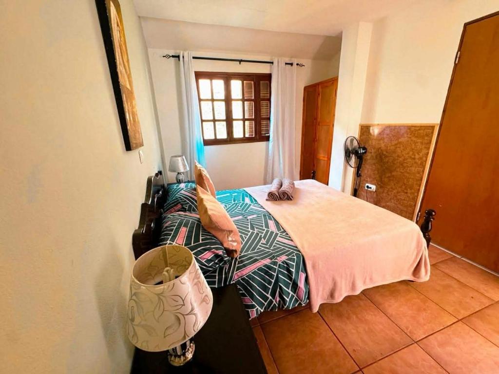 a bedroom with a bed with a pink blanket and a window at Divin'Art in Tarrafal da Vila de Ribeira Grande