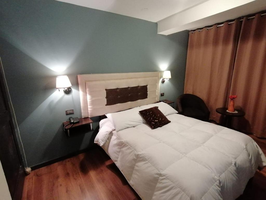 a bedroom with a white bed and a blue wall at Hotel Juan in Arequipa