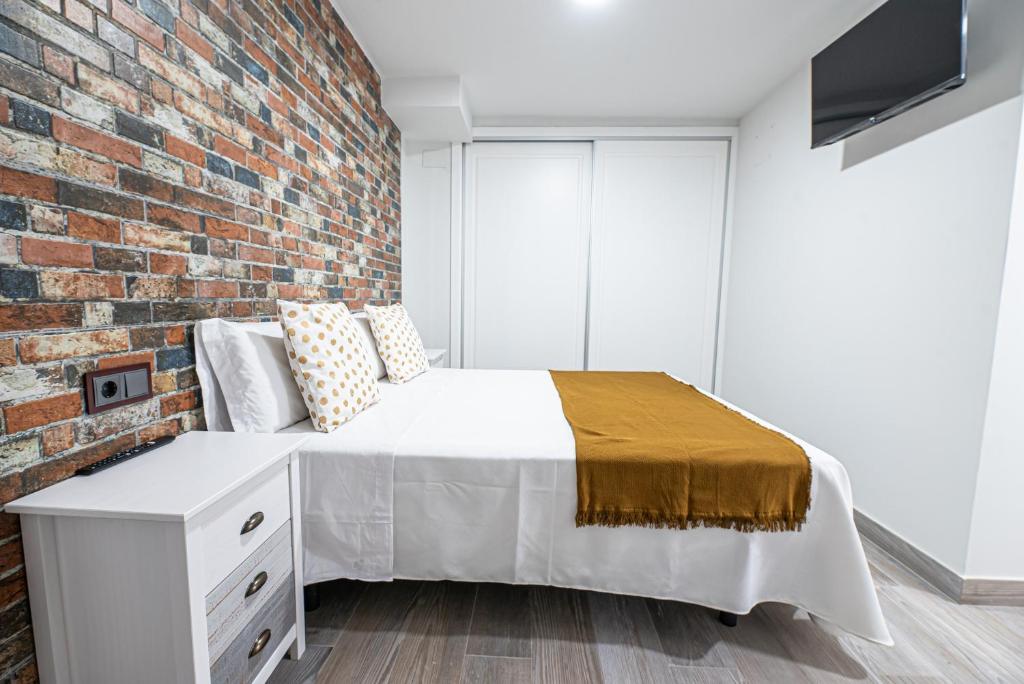 a bed in a room with a brick wall at Ocean Suites A6 in Isla Cristina