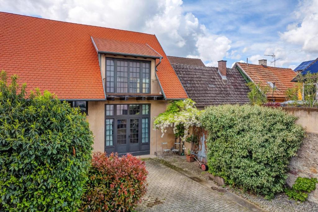an old house with an orange roof and bushes at Loft Im Künstlerhaus in Riegel am Kaiserstuhl